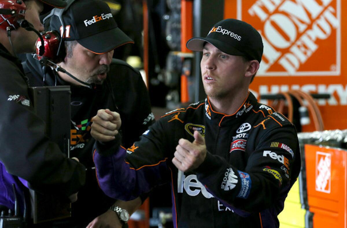 NASCAR driver Denny Hamlin talks to crew chief Darian Grubb in the garage during a practice session at Auto Club Speedway on Friday.