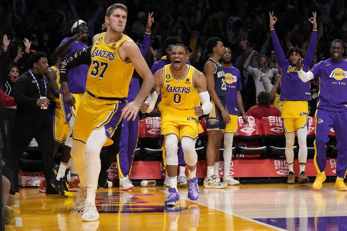 Matt Ryan looks to the side while Russell Westbrook smiles behind him and other Lakers raise their hands in the background.