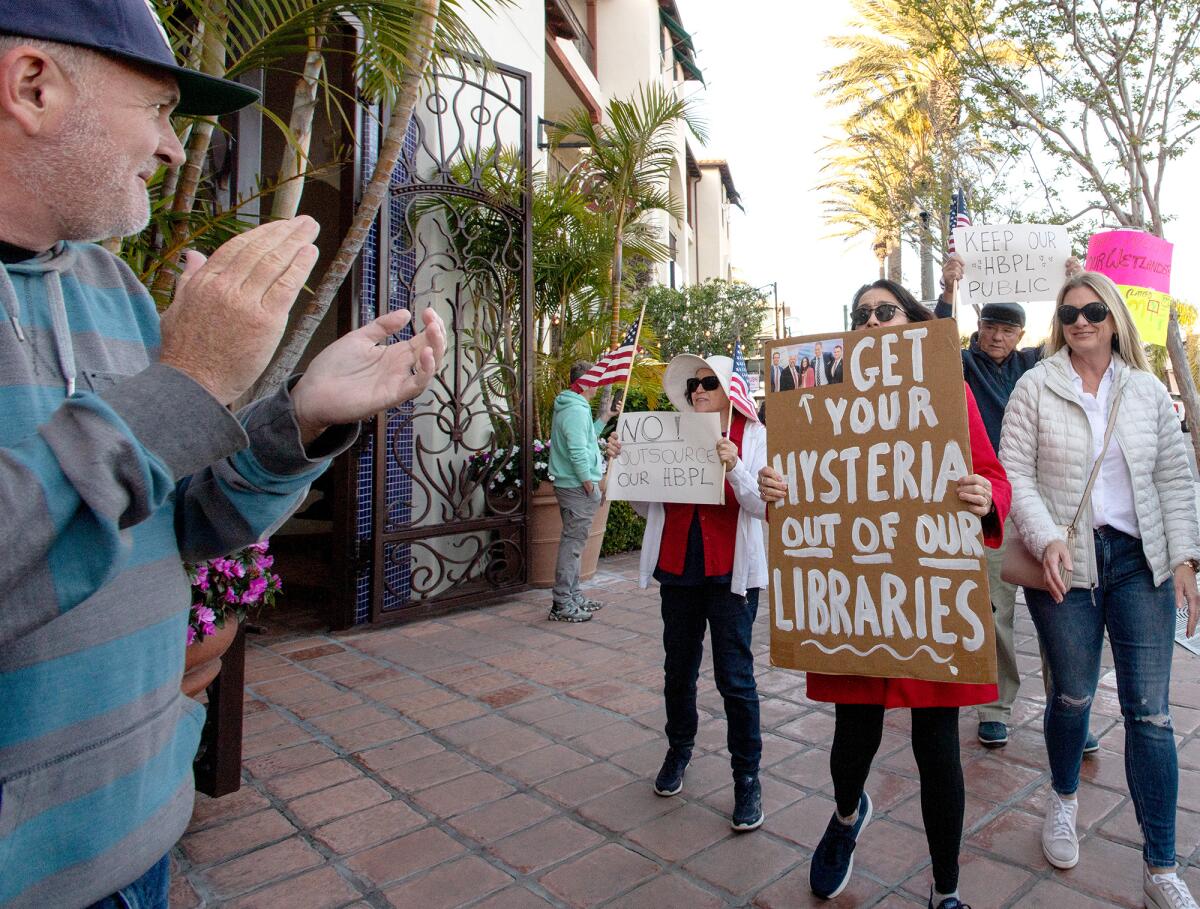 A man applauds a woman holding a sign