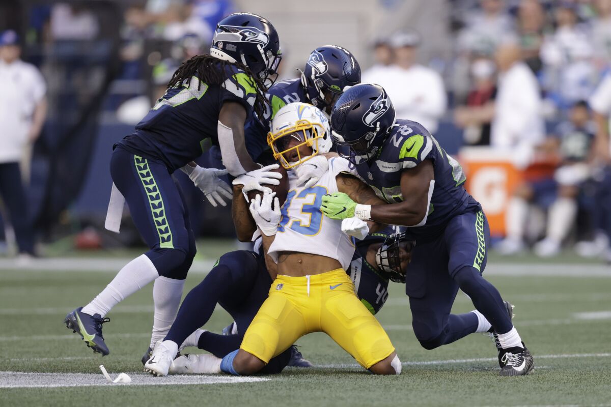 Los Angeles Chargers wide receiver Tyron Johnson, center, is brought down by Seattle Seahawks' Marquise Blair, Damarious Randall and Ugo Amadi, from left, during the first half of an NFL football preseason game Saturday, Aug. 28, 2021, in Seattle. (AP Photo/John Froschauer)