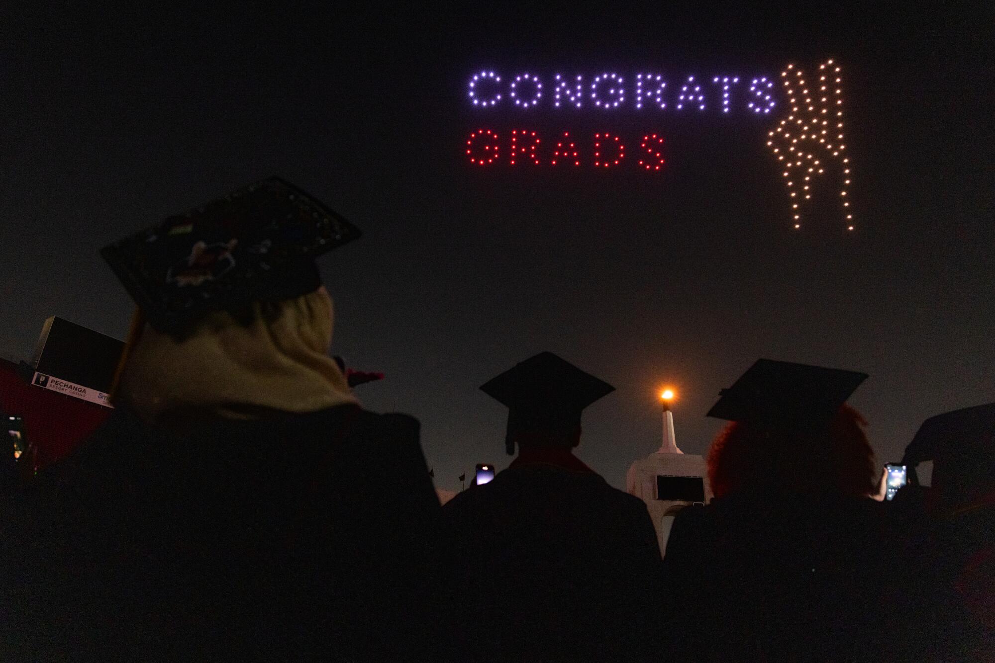 USC graduates watch as flying drones spells out "Congrats Grads."