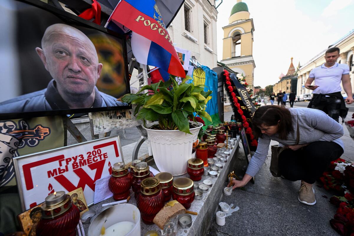 A woman lays a candle at a makeshist memorial for late head of Wagner paramilitary group, Yevgeny Prigozhin.