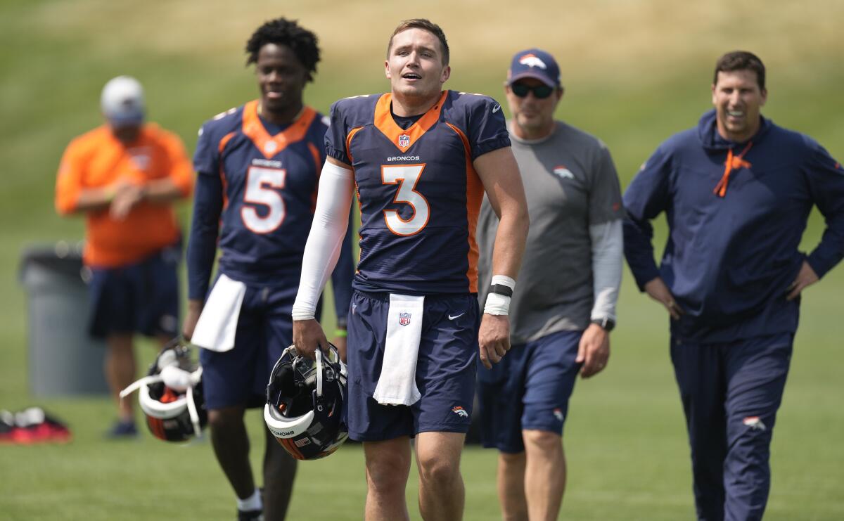 Denver Broncos quarterback Drew Lock, front, heads off the practice field with, from back left, quarterback Teddy Bridgewater (5), quarterbacks coach Mike Shula and offensive quality control coach Chris Cook after an NFL football training camp practice at the team's headquarters Tuesday, Aug. 10, 2021, in Englewood, Colo. (AP Photo/David Zalubowski)