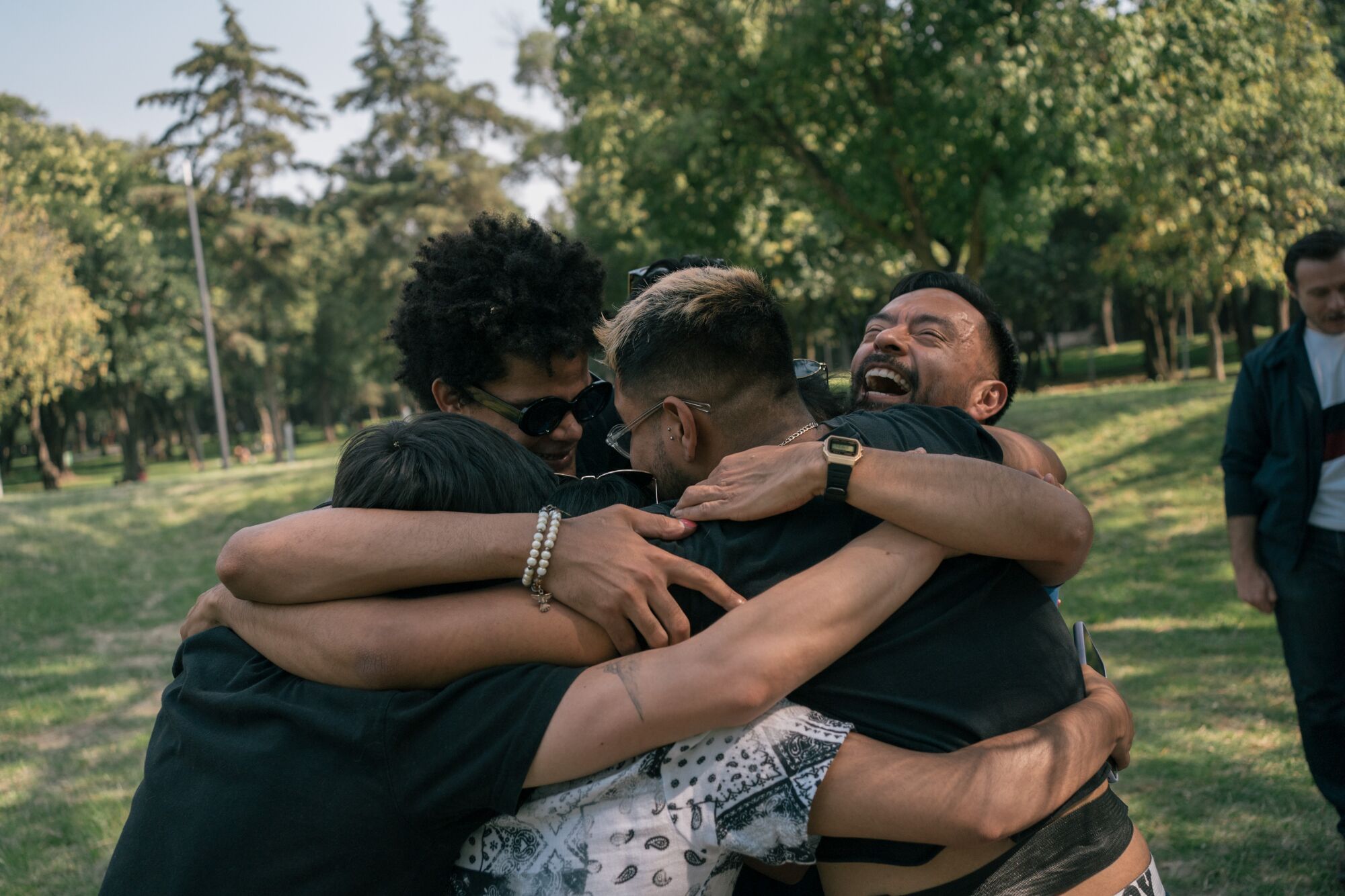 Several people share a group hug in a park setting 