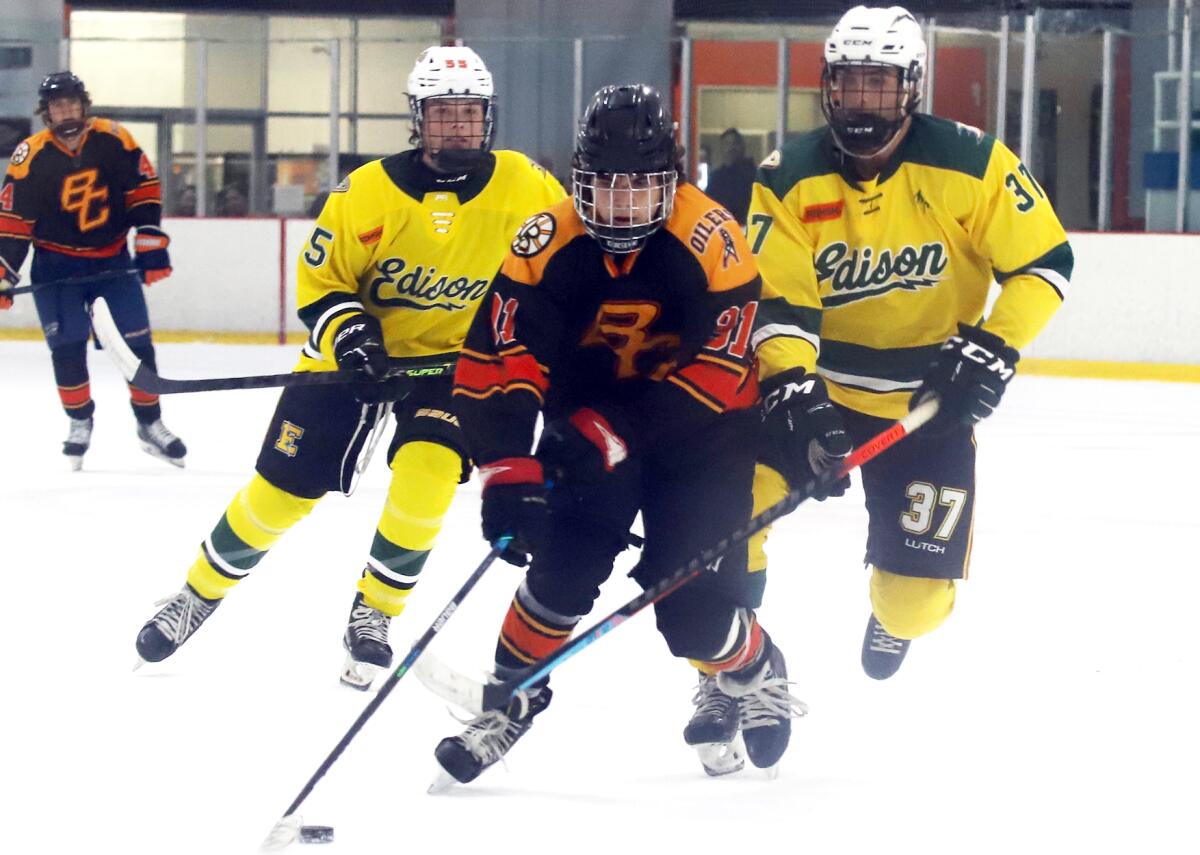 Beach Cities' Wallace Stirbu (91) breaks away from Edison defenders in an Anaheim Ducks High School Hockey League game.