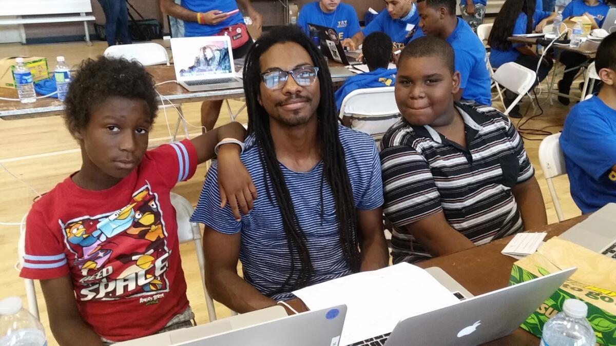 DeCarlis Wilson, center, helps children learn to code at a "hackathon" organized by Teens Exploring Technology at the Nickerson Gardens housing project in Watts.