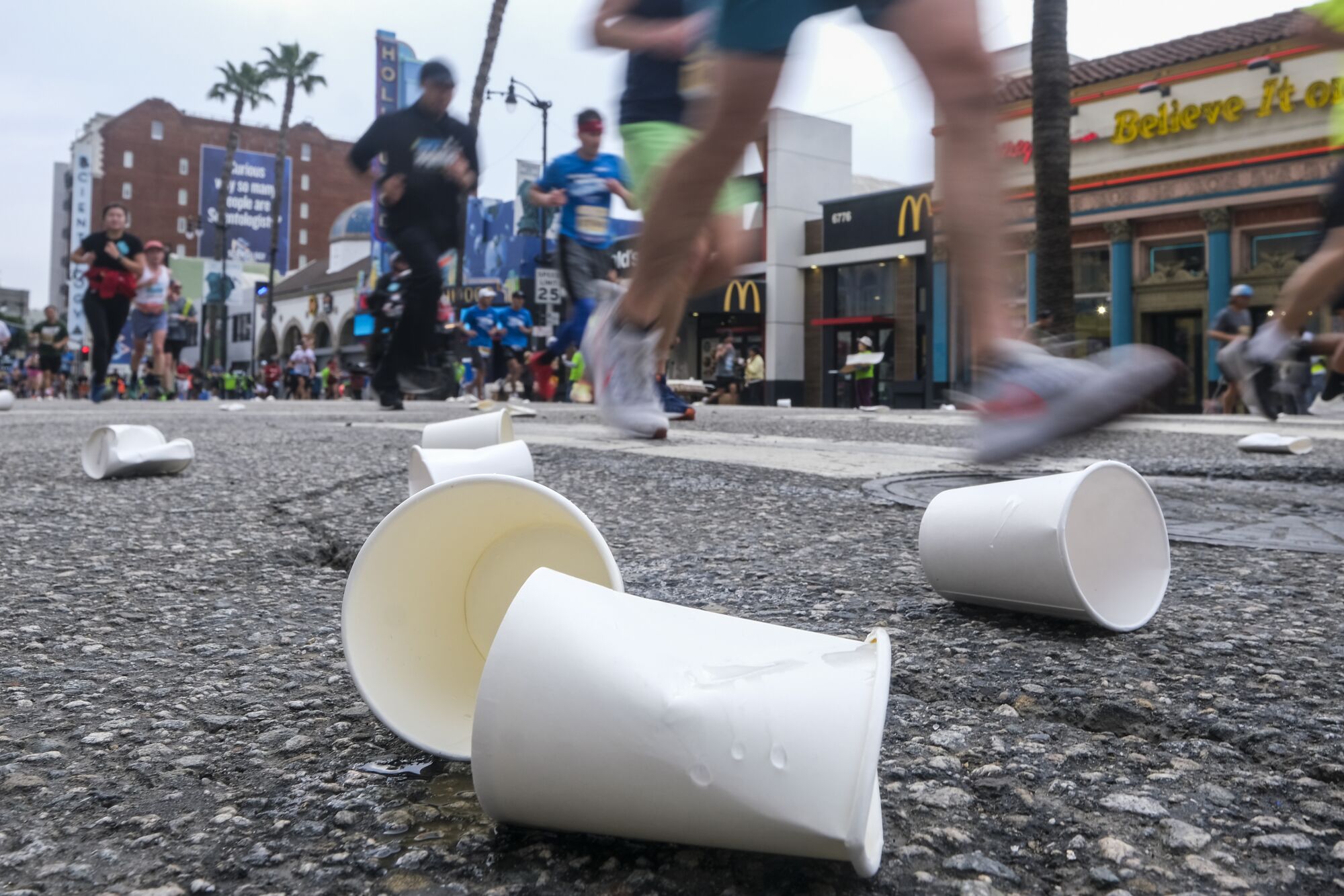 Water cups litter the street as runners pass them.