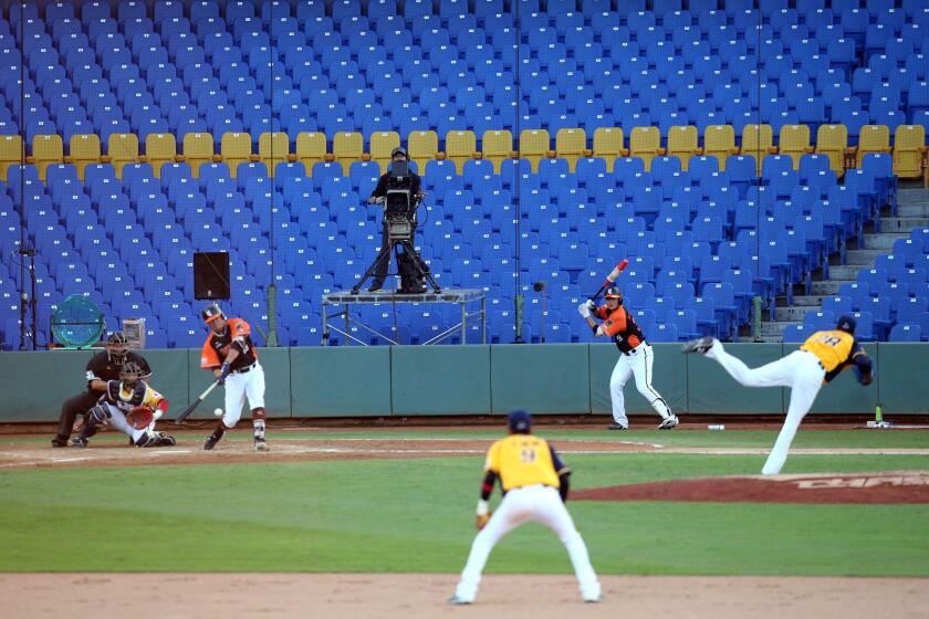 A broadcaster (C) operates a camera during the opening match between Uni President Lions against Chinatrust Brothers during the Chinese Professional Baseball League (CPBL) at the Taichung International Baseball Stadium on April 12, 2020. (Photo by Steven Lee / AFP) (Photo by STEVEN LEE/AFP via Getty Images)