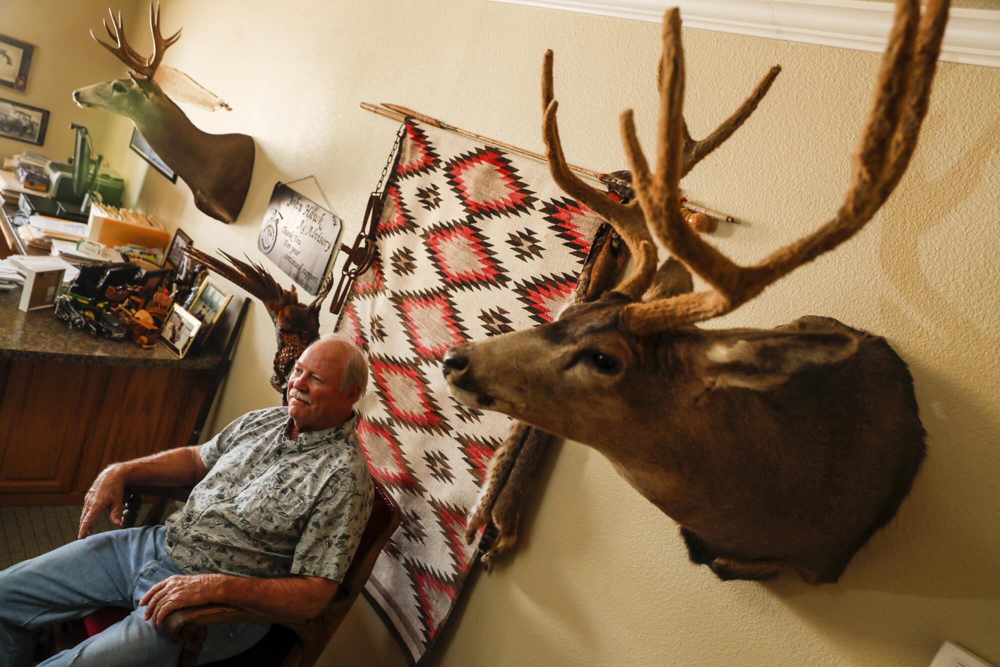 John Hawk sits at his company's office in Holtville, where taxidermy decorates the walls.