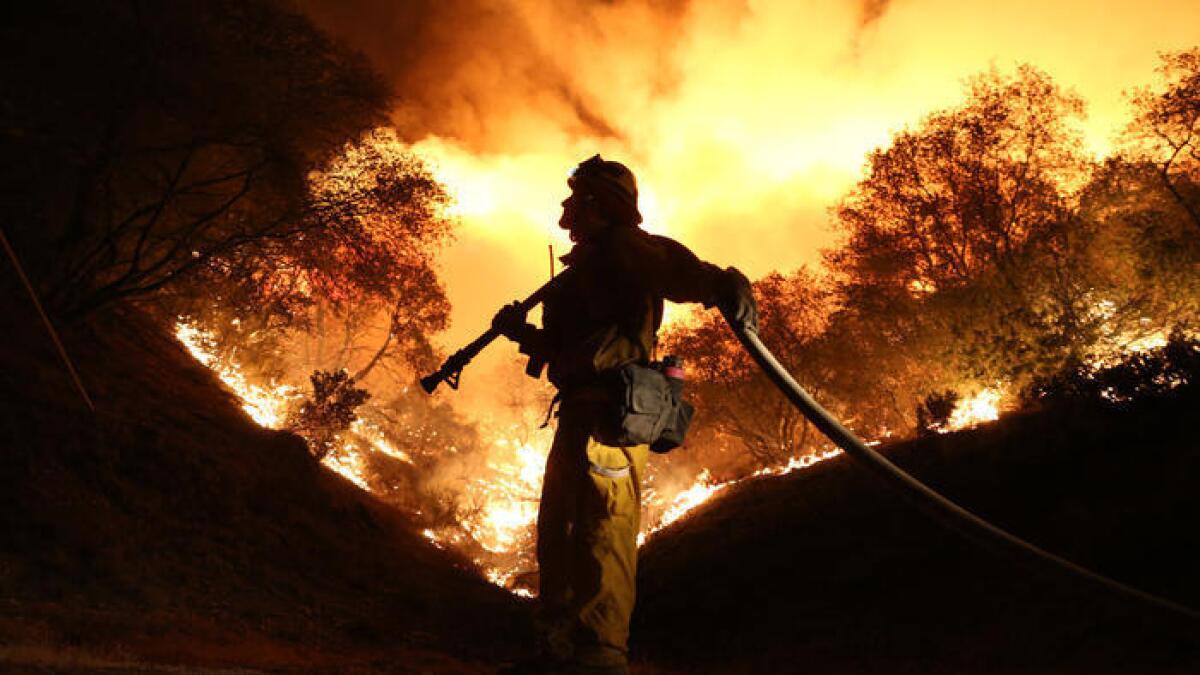 Andrew Dodds atiende la línea de agua mientras que los bomberos trabajan para iniciar una línea de fuego para contener el incendio Butte en Fricot City Road cerca de Sheeps Ranch, en California, el 12 de septiembre.