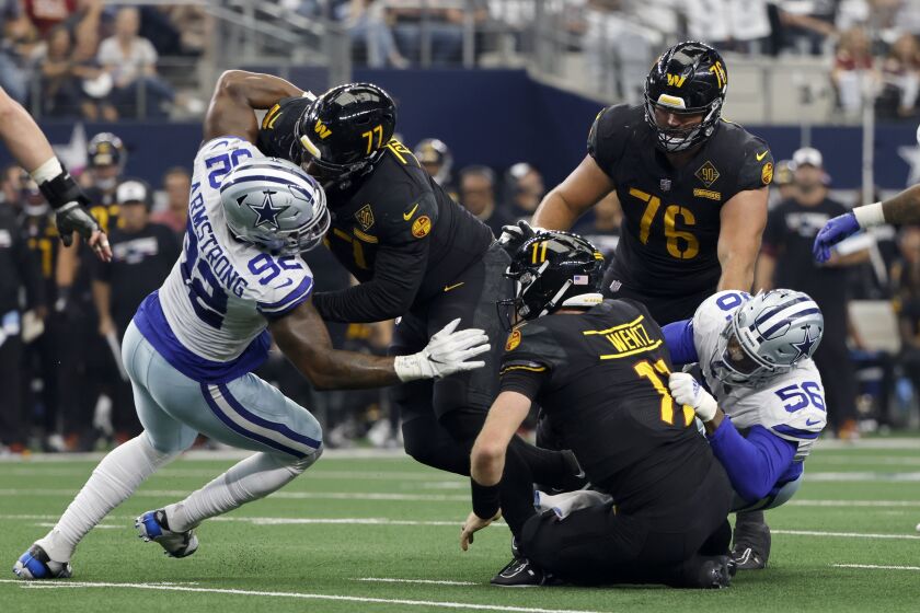 Dallas Cowboys defensive end Dante Fowler Jr. (56) sacks Washington Commanders quarterback Carson Wentz (11) as Dorance Armstrong (92) pressures and Saahdiq Charles (77) and Sam Cosmi (76) defend in the second half of a NFL football game in Arlington, Texas, Sunday, Oct. 2, 2022. (AP Photo/Ron Jenkins)