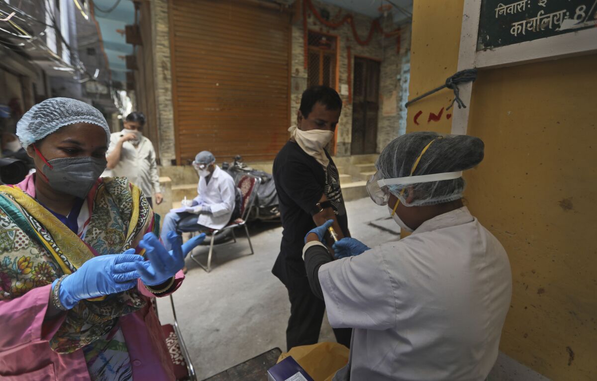 Health workers take blood samples for a random serological test to check for antibodies against the coronavirus in New Delhi, India, Thursday, Aug. 6, 2020. A serological survey is currently underway to undertake a comprehensive analysis of COVID-19 in Delhi and prepare strategies to combat the pandemic. (AP Photo/Manish Swarup)