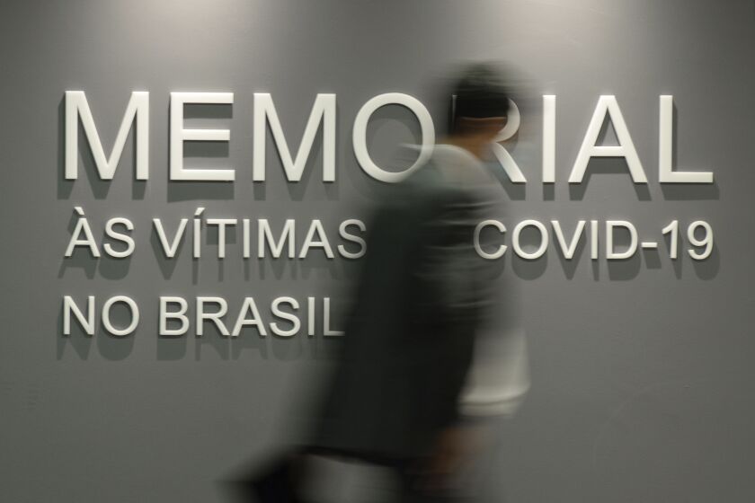 Un hombre camina frente a un muro que dice en portugués: "Memorial para las víctimas del COVID-19 en Brasil", en el edificio del Senado en Brasilia, Brasil, el martes 15 de febrero de 2022. (AP Foto/Claudio Reis, Archivo)