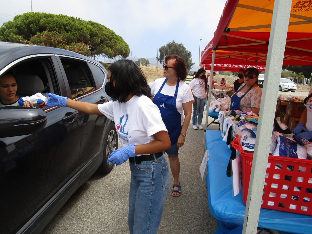 Assistance League members Nataly Solano and Sheila Jones hand out school supplies to families at Camp Pendleton.