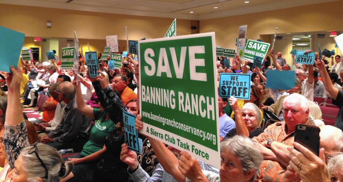 Members of the Banning Ranch Conservancy from Newport Beach, Costa Mesa and Huntington Beach raise signs in support of the California Coastal Commission staff recommendation that the commission deny the Banning Ranch development project during its meeting Wednesday in Long Beach.