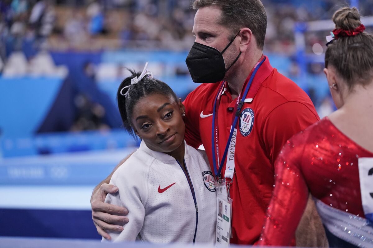 Coach Laurent Landi embraces Simone Biles after she exited the team final with apparent injury Tuesday