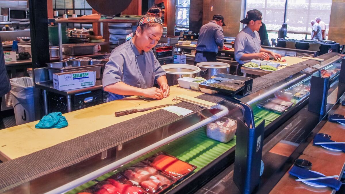 Sushi chefs Pae Randall (left) and Von Puyaoan meticulously create the innovate sushi rolls that Café Japengo became known.