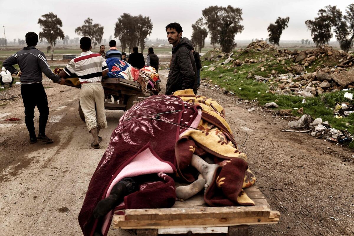 Relatives transport the bodies of Iraqi residents who were killed in an airstrike targeting Islamic State jihadists in west Mosul on March 17, 2017.