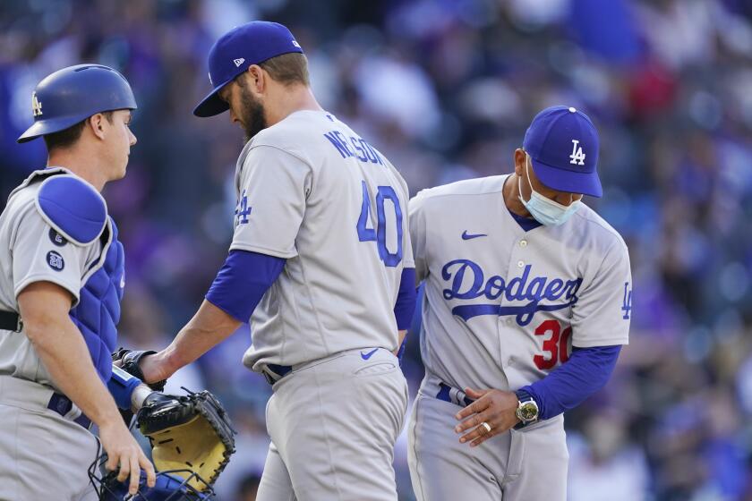 Los Angeles Dodgers manager Dave Roberts, right, pulls relief pitcher Jimmy Nelson as catcher Will Smith looks on after Nelson gave up an RBI-single to Colorado Rockies' Raimel Tapia in the seventh inning of a baseball game Thursday, April 1, 2021, in Denver. (AP Photo/David Zalubowski)