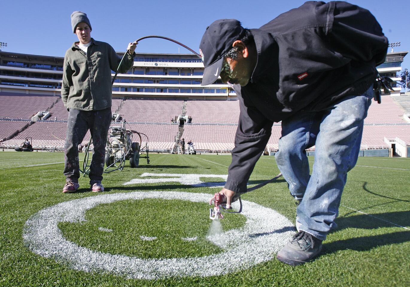 Martin Rodriguez, with the help of Dallas Hattox, paint the artwork at the 50-yard-line at the Rose Bowl in Pasadena on Thursday, December 20, 2012. Everything that goes into preparing for the upcoming Rose Bowl football game takes place on a schedule, behind the scenes, so the experience for all who attend, including fans, players, coaches, and other guests, is safe and fantastic.