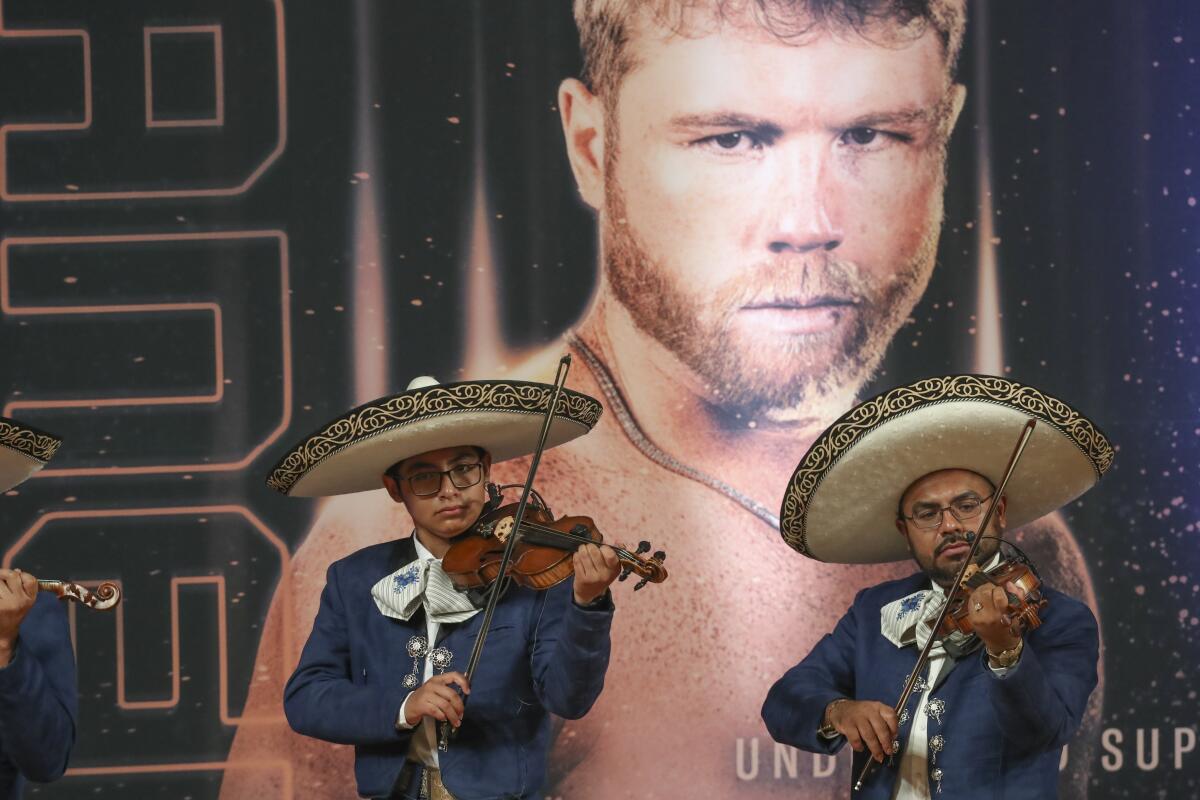 Mariachis perform in front of a poster featuring boxer Saul "Canelo" Álvarez