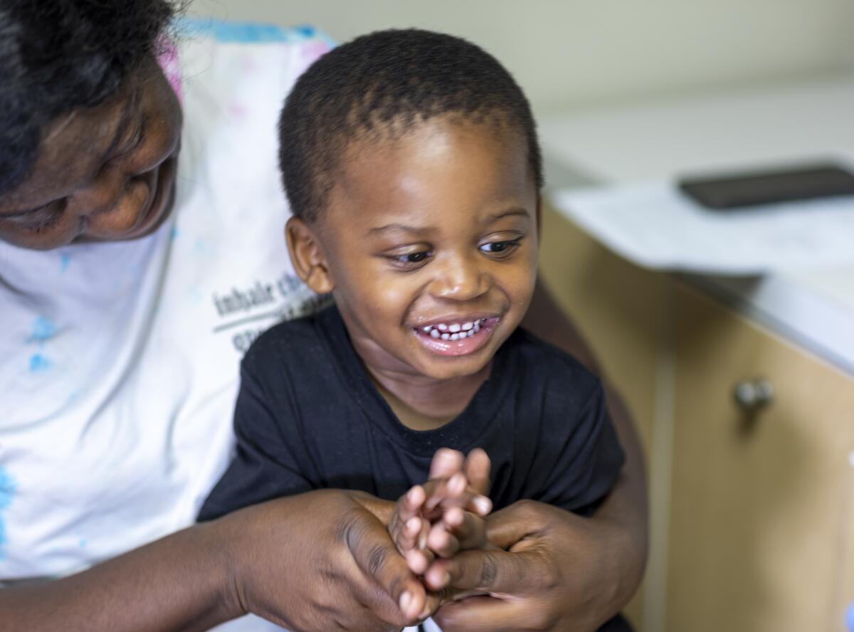 A smiling child sits in his mother's lap.