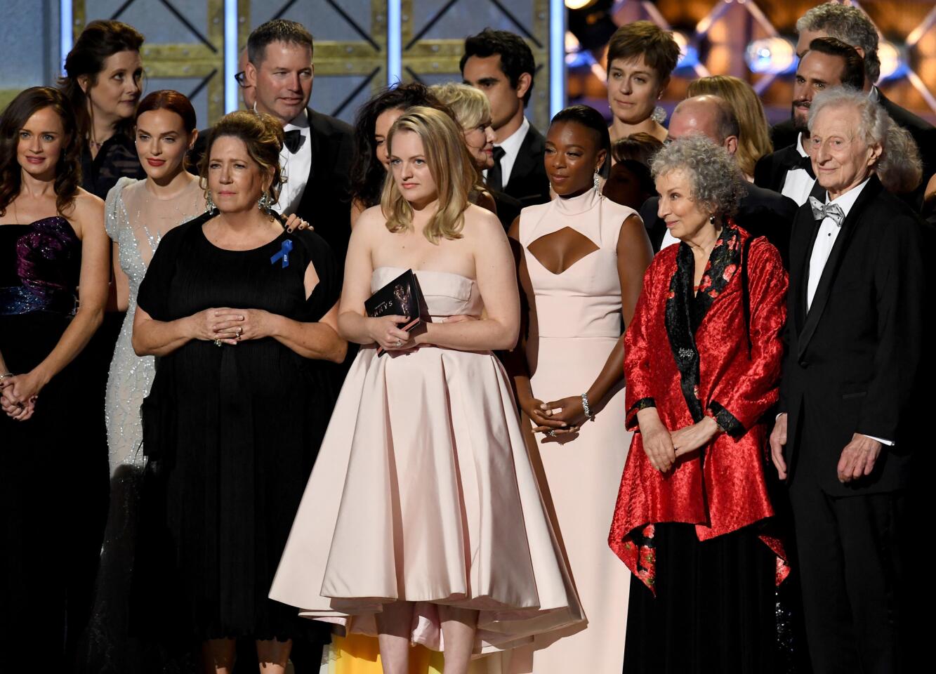 Actress Elisabeth Moss, center, and author Margaret Atwood (in red) with cast and crew of "The Handmaid's Tale" accept the drama series award onstage.