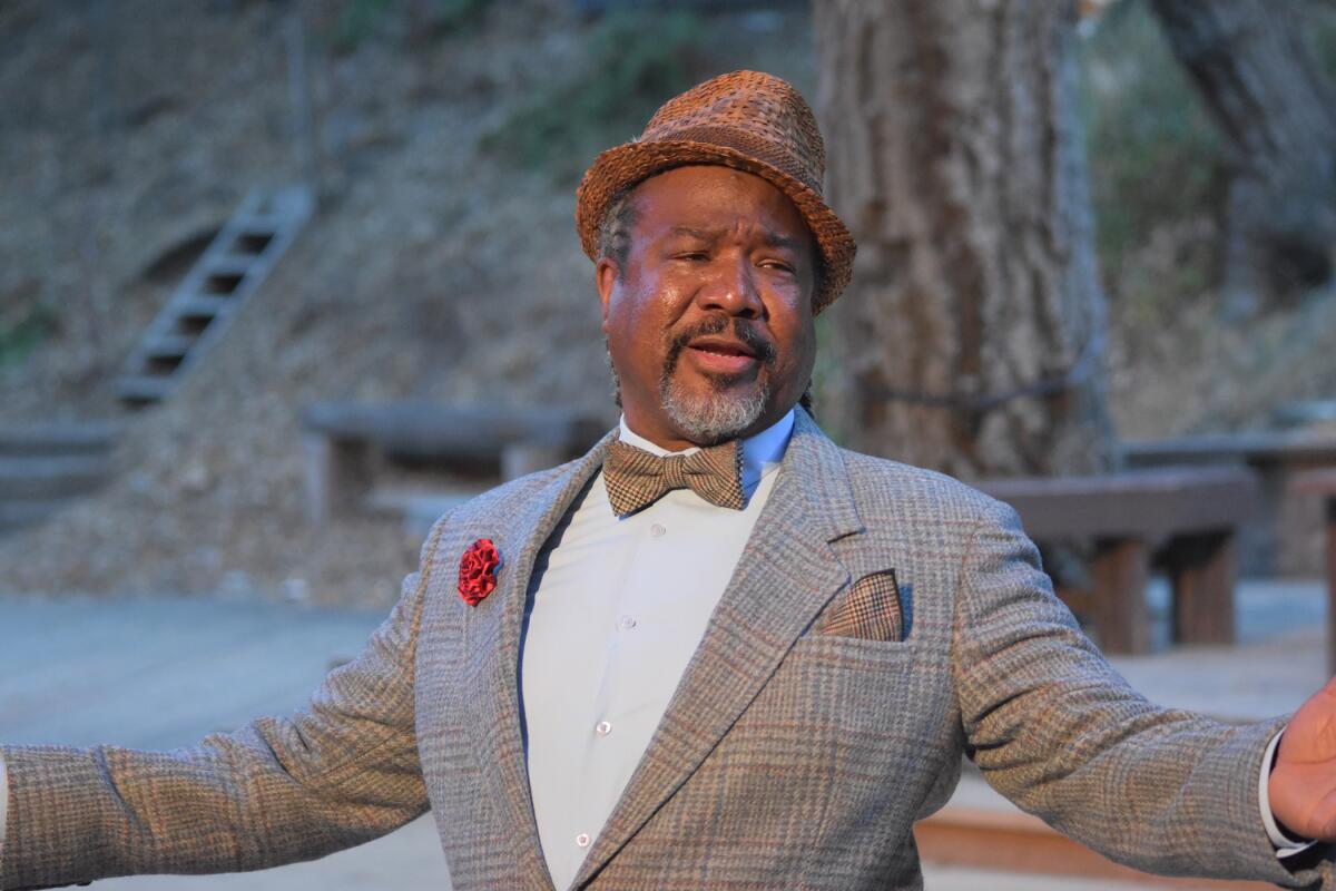 A man in a fedora and bow tie with his arms outspread