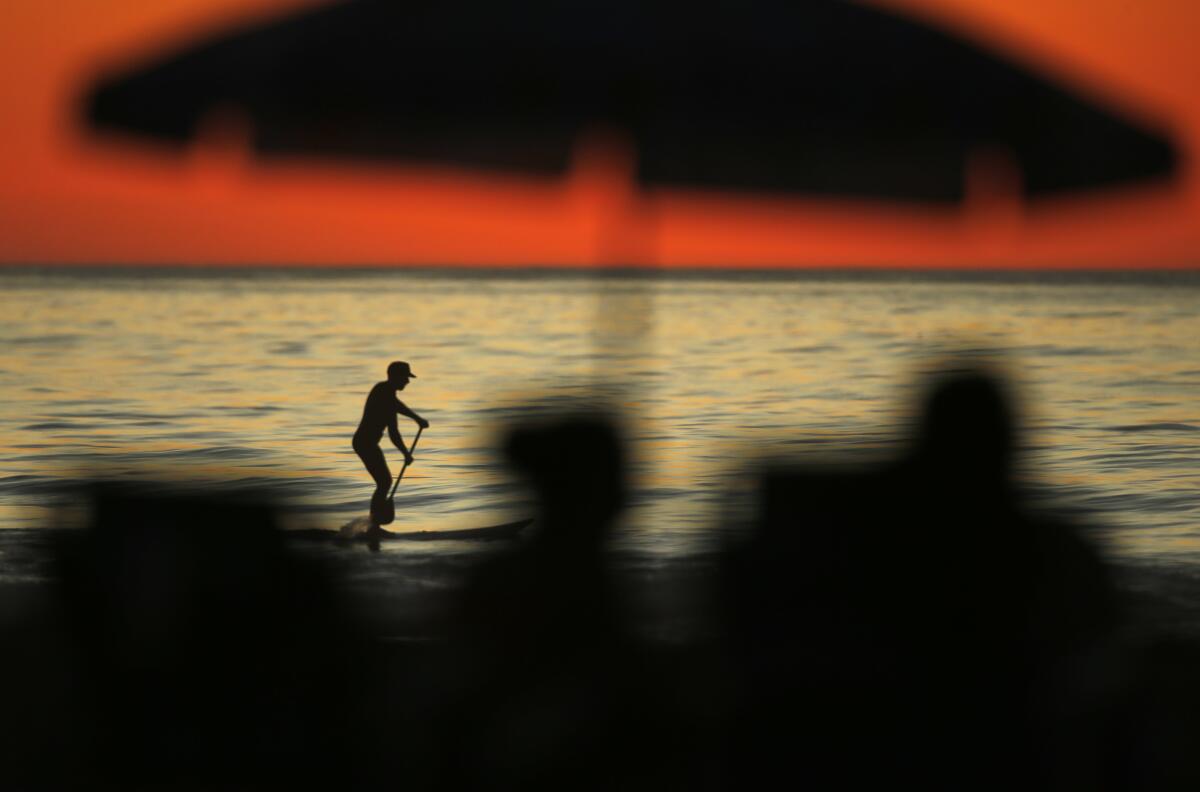 A paddle boarder moves across the ocean water at La Jolla Shores.