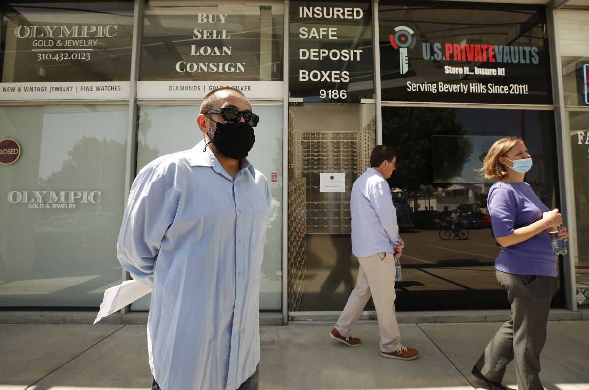 A masked man holding papers stands outside a store