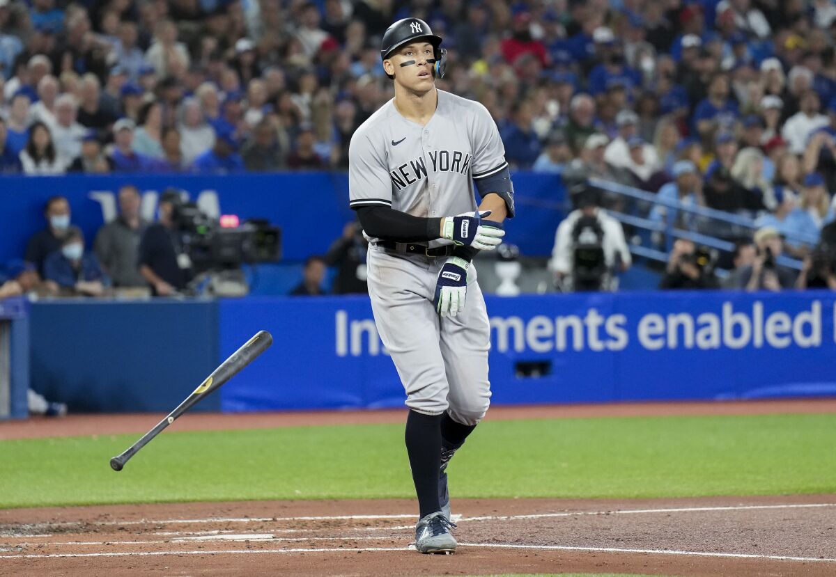 New York Yankees' Aaron Judge tosses his bat as he is walked by Toronto Blue Jays starting pitcher Kevin Gausman during third-inning baseball game action in Toronto, Monday, Sept. 26, 2022. (Nathan Denette/The Canadian Press via AP)