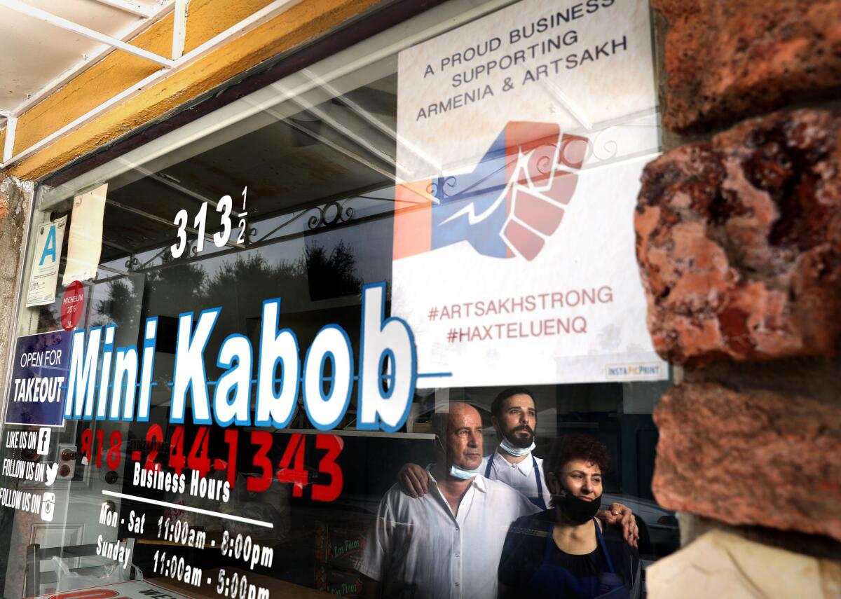 Three people reflected in the window of a kabob restaurant