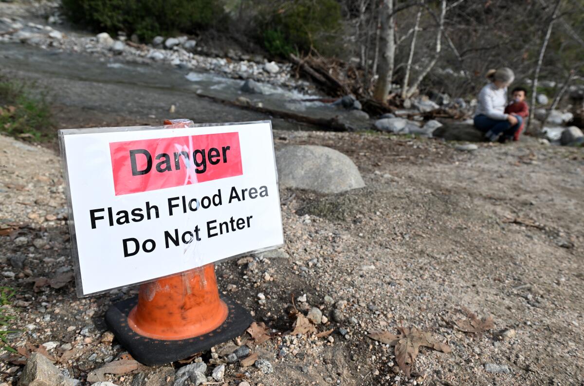 A sign posted to a traffic cone reading "Danger: Flash Flood Area; Do Not Enter"