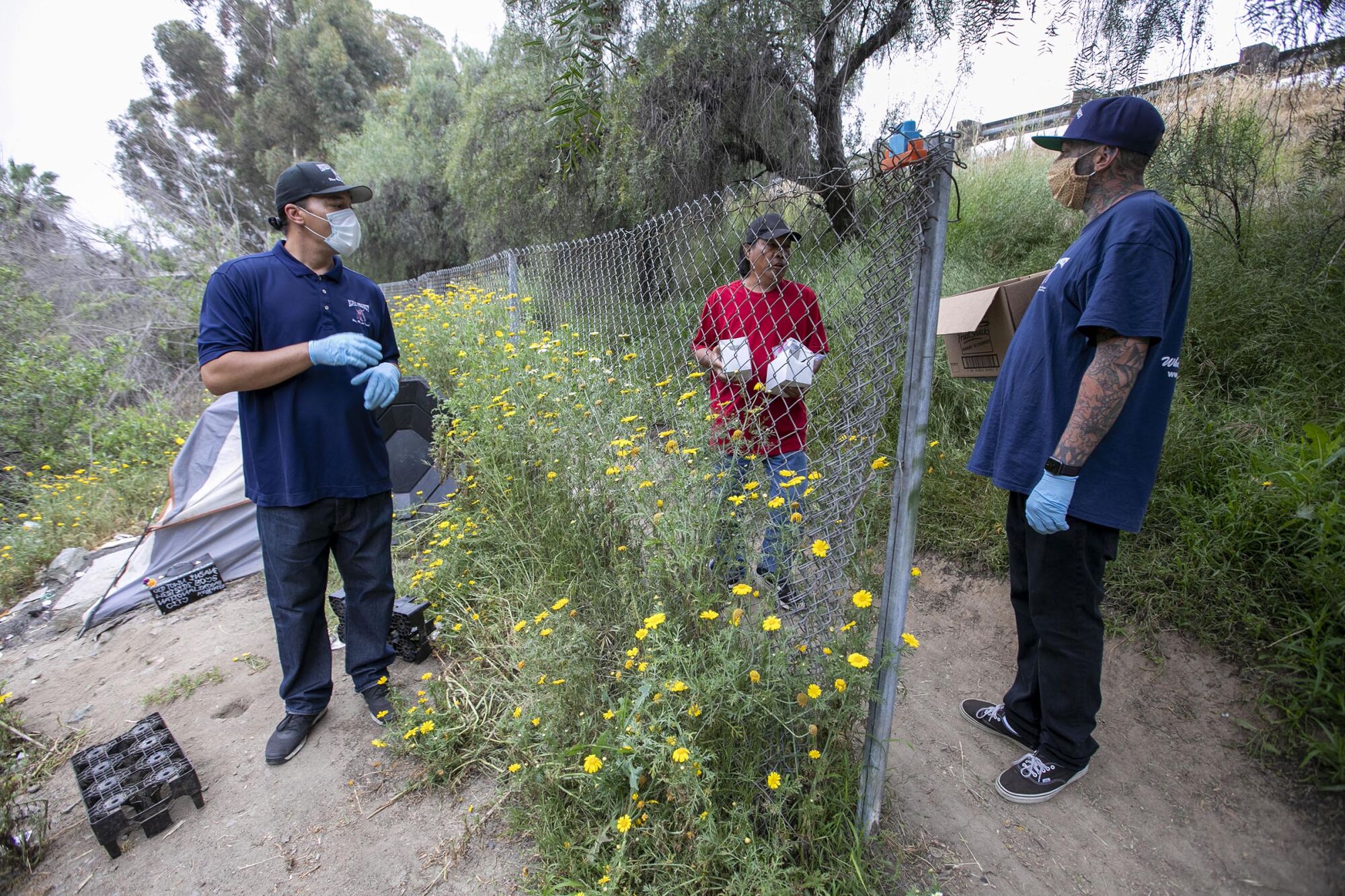 Alpha Project outreach workers, Anthony Aquiningoc, left, and Nick Healy, right, speak with 59 year-old Remigio "Toto" Julio who has been living in the Sweetwater River bottom by the Plaza Bonita mall in National City for the last seven months on Friday, April 30, 2020. Later in the day they took him to the Convention Center shelter.