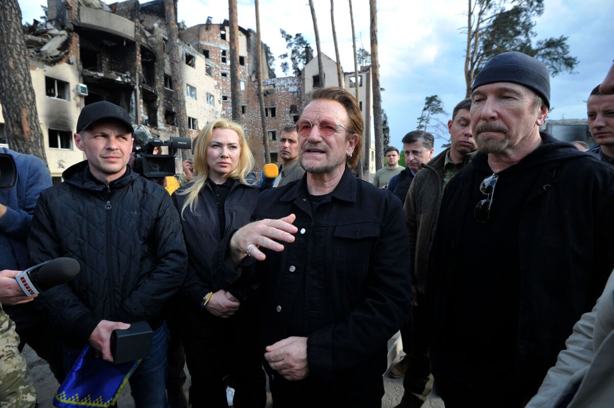 Surrounded by bombed and burned buildings, Bono and the Edge greet Ukrainians on Sunday in the town of Irpin, near Kyiv.