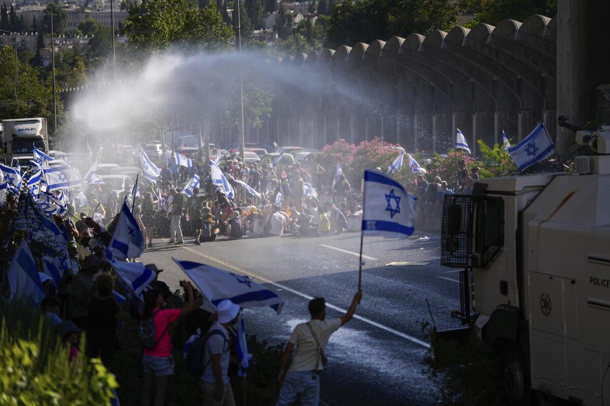 Israeli police use a water cannon to disperse demonstrators blocking a road.