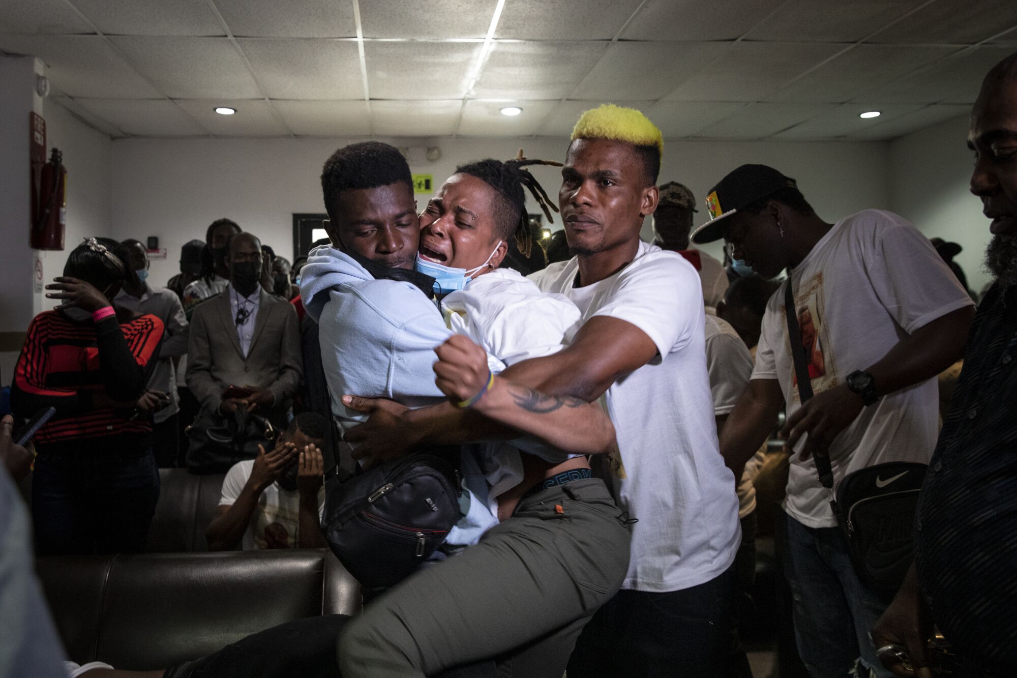 Pethou Archange, center, mourns the loss of her brother.