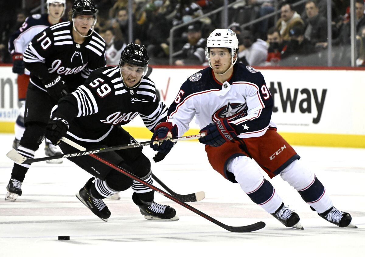 Columbus Blue Jackets center Jack Roslovic (96) and New Jersey Devils left wing Janne Kuokkanen (59) chase after the puck during the second period of an NHL hockey game Thursday, Jan. 6, 2022, in Newark, N.J. (AP Photo/Bill Kostroun)