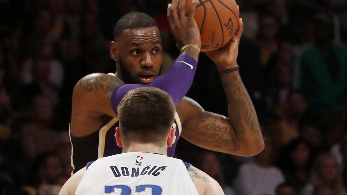 Lakers forward LeBron James looks for a path to the basket against Mavericks forward Luka Doncic in the first quarter.