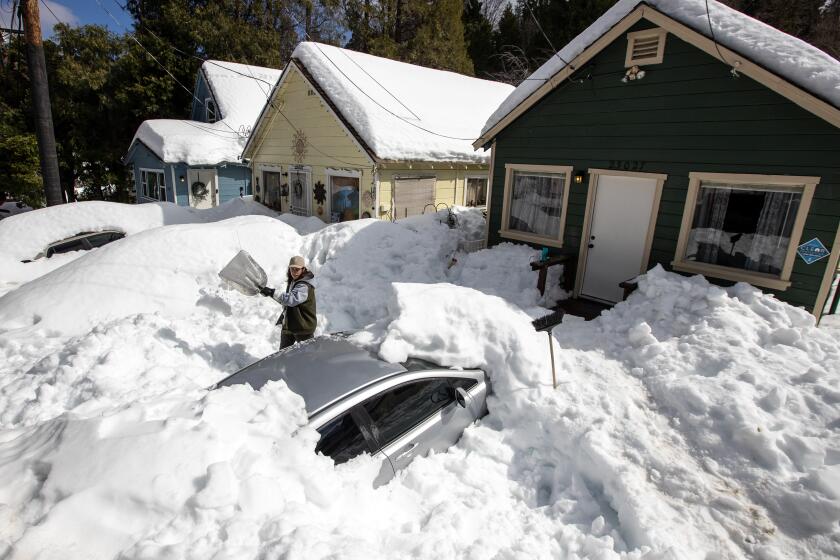 CRESTLINE, CA - MARCH 07: Kadyn Wheat, 14, shovels snow as he works to free the family car, entombed after successive snow storms paralyzed the region in the San Bernardino Mountain community on Tuesday, March 7, 2023 in the Valley of Enchantment, CA. (Brian van der Brug / Los Angeles Times)