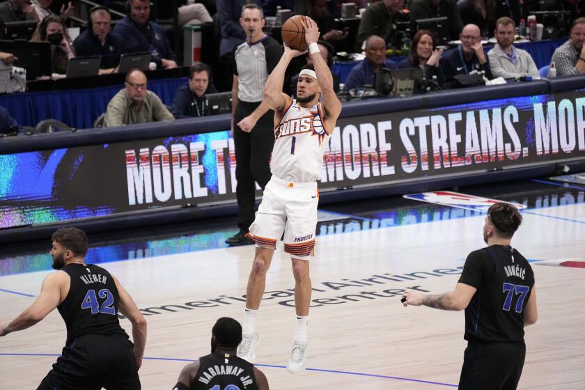 Devin Booker (1), de los Suns de Phoenix, toma un tiro ante la mirada de tres jugadores de los Mavericks de Dallas, Maxi Kleber (42), Tim Hardaway Jr. (10) y Luka Doncic (77) en la segunda mitad del juego de baloncesto de la NBA, en Dallas, el miércoles 24 de enero de 2024. (AP Foto/Tony Gutierrez)