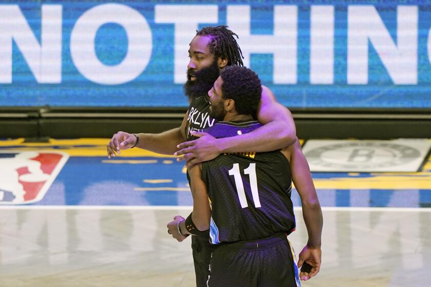 Brooklyn Nets guard James Harden (13) embraces guard Kyrie Irving (11) after Irving scored on a play during the second quarter of an NBA basketball game against the Orlando Magic, Thursday, Feb. 25, 2021, in New York. (AP Photo/Kathy Willens)