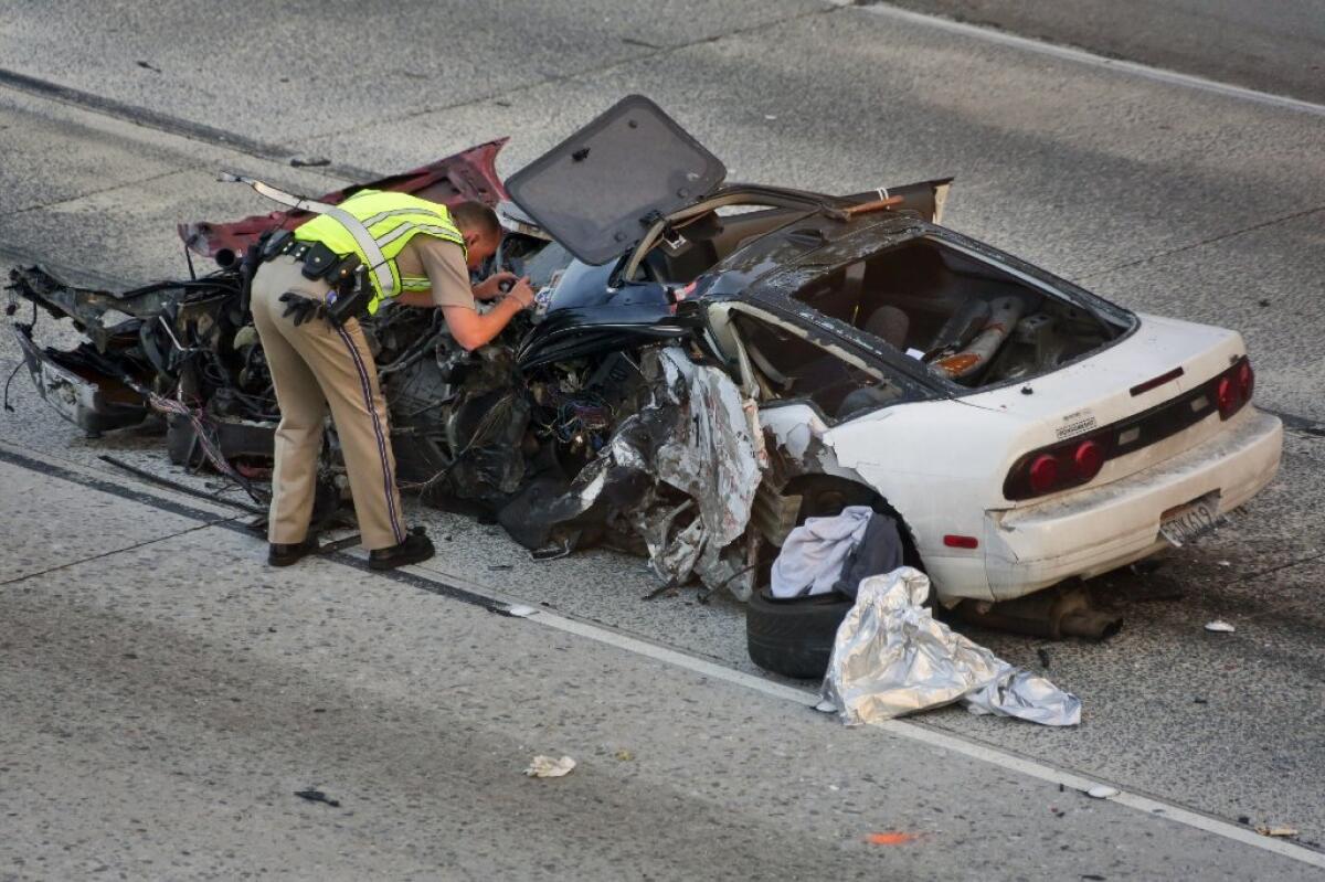 A CHP officer inspects the car of a motorist killed by a wrong-way driver on the 210 Freeway in Azusa early Saturday.