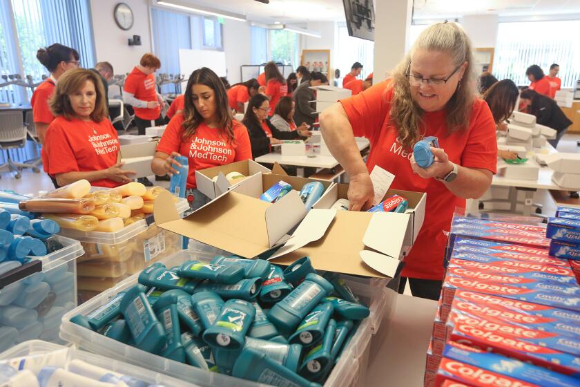 Volunteer Wendy Cardinale, a senior manager, right, fills two hygiene kits.