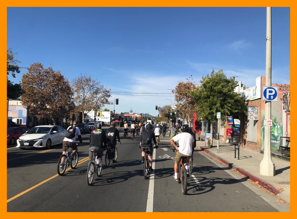 A biking group rides through a city block.