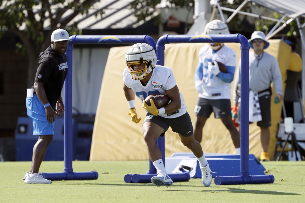 Chargers running back Austin Ekeler (30) runs in a drill while wearing a new protective practice helmet.