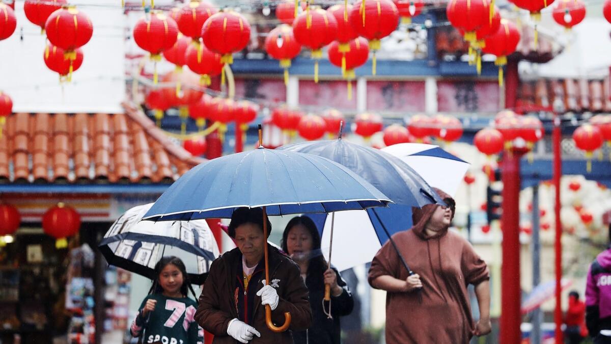 Visitors to downtown Los Angeles' Chinatown walk in the rain Saturday. Another atmospheric river-fueled storm is expected to hit Southern California on Tuesday.