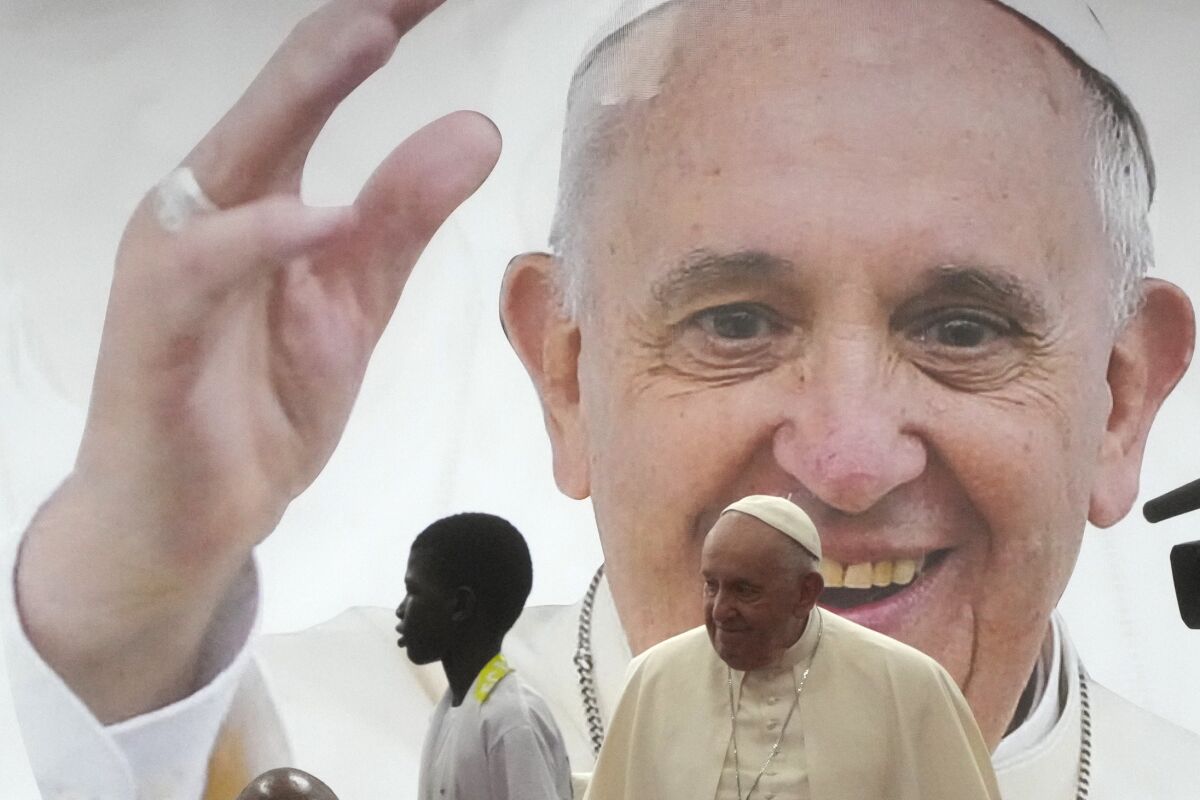 Pope Francis and a boy in front of a giant photo of the pope