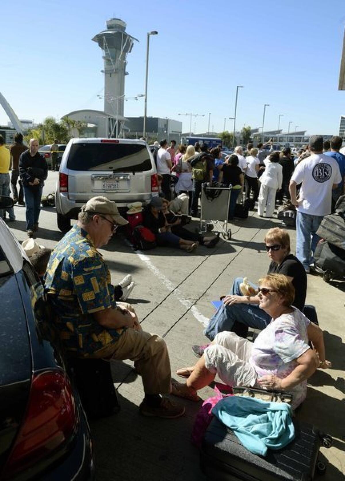 Passengers wait outside LAX Terminal 1 after thousands were evacuated after a shooting in Terminal 3.