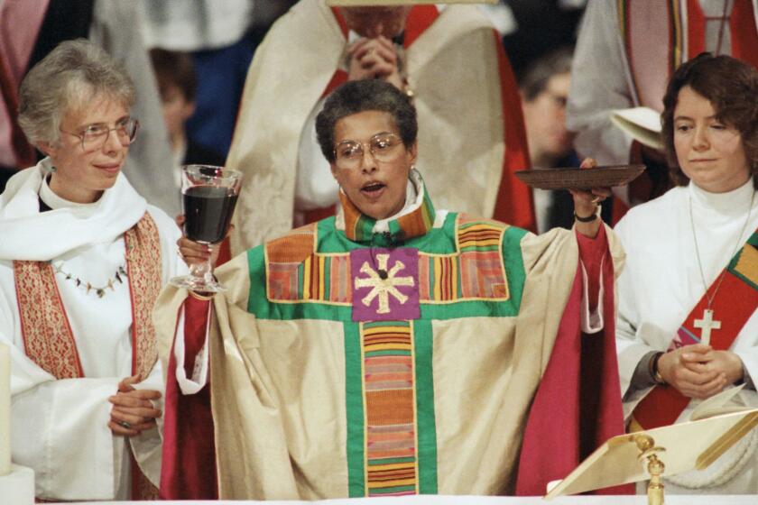 Bishop Barbara Harris, center, celebrates the Eucharist at the ceremony for her ordination and consecration as the first woman bishop in the history of the Episcopal Church, at the Hynes Convention Center in Boston, Feb. 11, 1989. At left is Rev. I. Carter Heyward. Celebrant at left is unidentified. (AP Photo/Peter Southwick)